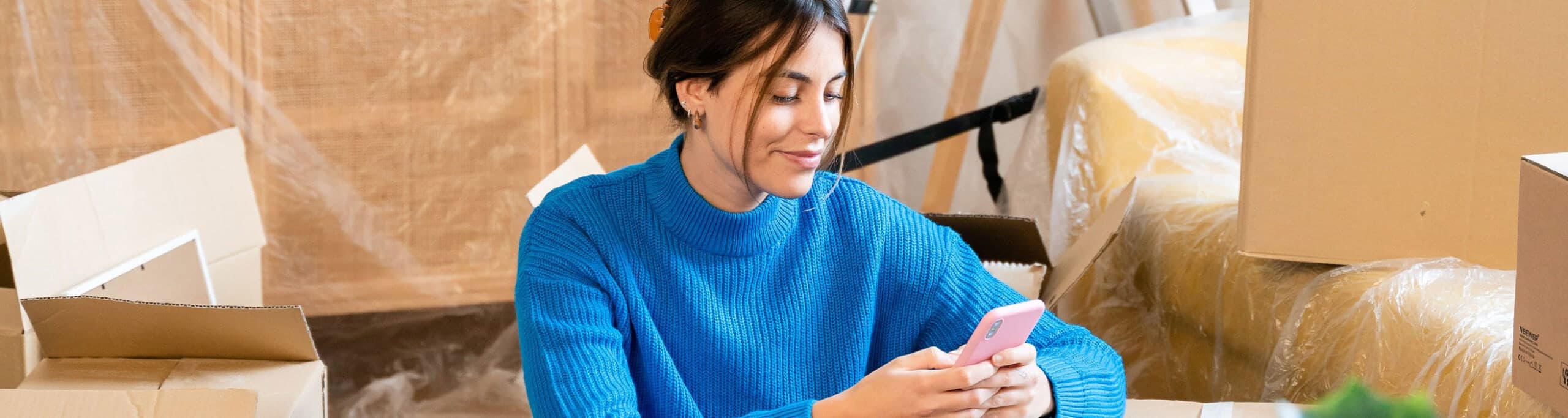 A woman sitting next to moving boxes - House Key Spring 2024 Magazine - United Van Lines